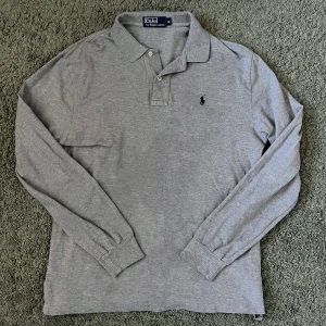 Ralph Lauren Pikétröja - Grå långärmad piké från Ralph Lauren. inga defekter och i storlek M. Kan mötas i sthlm!