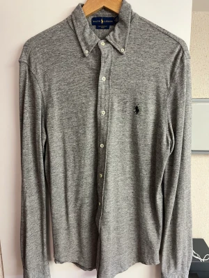 Ralph Lauren skjorta  - Säljer grå Polo Ralph Lauren skjorta i storlek M. Jag är 185 cm och passformen är normal ( möjligtvis lite tightare ) men inte mycket. Lite tjockare material