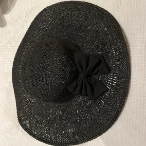 Solhatt - Svart solhatt. Helt ny aldrig använd. Glömde skicka tillbaka då den var för liten för mig. Rosetten sitter inte på men kan tillkomma vid förfrågan.