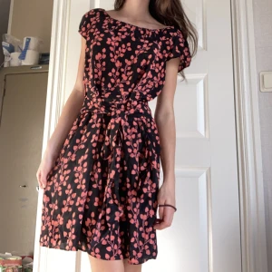 Klänning  - Helt ny klänning med röd/rosa löv växter. Den har snören så man kan knyta rosett längst fram eller bak🫶🏼 Skulle säga att den är lite off shoulder vid axlarna. Köpt från märket Limited Collection som inte längre säljer denna klänning🌟
