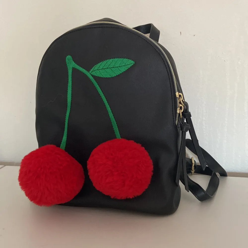 Jättegullig ryggsäck med körsbär på! Rymlig och aldrig använd.   Cirka 22 cm hög och 19 cm bred . Väskor.