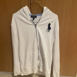 Ralp Lauren tröja - Säljer denna vita Ralph Lauren tröja med en blårandig insida av luvan. Storlek XL för barn men funkar som S/M i vuxenstorlek. Säljer för 270kr