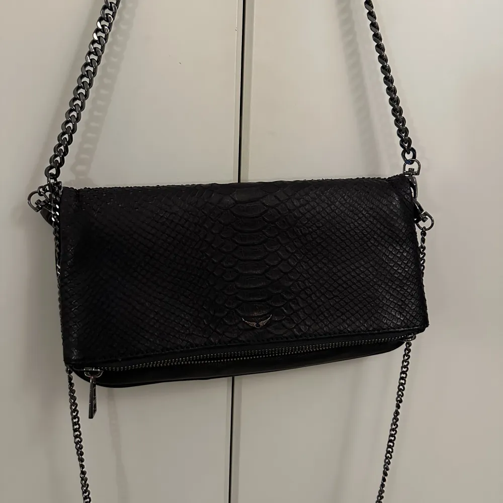 Säljer min fina väska från Zadig & Voltaire i super fint skick. Den är i modellen soft Savage Rock Clutch. Man får med två stycken axelremmar i olika längder. Den kostar ungefär 4500kr ny.☺️. Laukut & Käsilaukut.