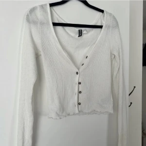 Tröja - Vit tunn virkad tröja/kofta från H&M med knappar som gör att man kan styla den som man vill, hur urringad den ska vara, men man kan också använda den som en kofta. Knappt använd