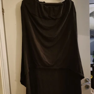 Lång svart kjol  - Svart kjol, kort fram, lång bak. Fram ca 55cm, bak ca 100cm. Ca 90cm i midjan. Resår i midjan, stretchigt material. Knappt använd.