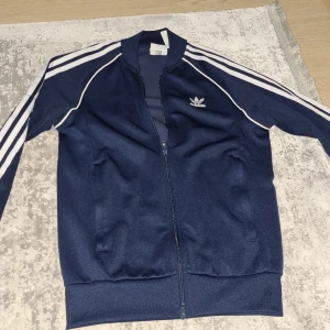 Blå Adidas kofta  - Den är i gott skick men tyvärr har jag växt ifrån och blivit större och den är köpt för 799 kr. (Äkta)