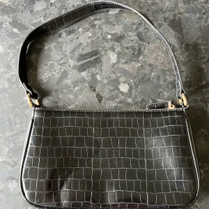 Väska - En svart väska med guld detaljer. Köpt för några år sen, vet inte vilket märke. 