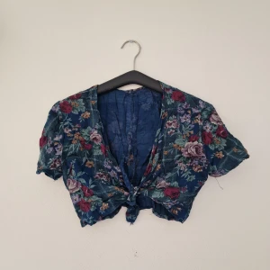 Blommig knyt t-shirt - Blommig knyt t-shirt. Tror det är linnetyg 🥰 (för referens har jag ca 80 cm runt bröstkorgen)