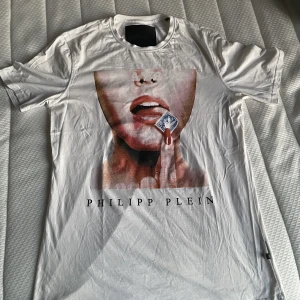 Philipp Plein Playboy tshirt - Jag säljer tröjan då jag inte längre använder den, T-shirten är använd ett par gånger men är i bra skick förutom att texten på ryggen slitits lite (se bild). Tröjan är i storlek XXL men sitter ganska tajt. Kan mötas upp i Göteborg eller posta tröjan