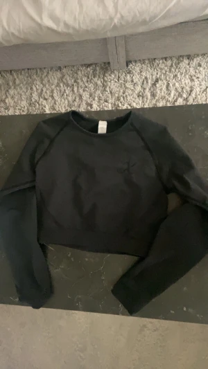 Långärmad, croppad träningströja - Långärmad, croppad träningströja från Xshapes i svart säljes då den blivit för liten för mig. Använd 1-2 gånger, nyskick.