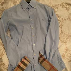 Säljer nu en väldigt eftertraktad och trendig skjorta ifrån burberry! Som är välsköten och i bra skick! XS - Ljusblå  SKICK 9/10 Endast andvända några gånger under resturang besök eller liknande!