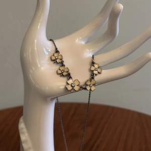Superfint halsband från pilgrim i en mörkare metall med elfenbensvita klöverberlocker. Passar perfekt att matcha med t.ex. pärlhalsband!