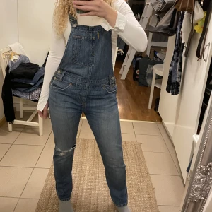 Hängselbyxor  - 🦋Så snygga snickarbyxor ifrån Levis. En slitning på höger knä och hål på det vänstra knät. Använda fåtal gånger så väldigt fint skick🦋