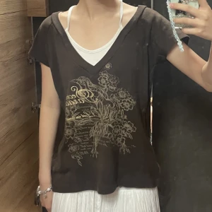 brun vintage y2k tröja - superfin kortärmad tröja med unikt tryck köpt second hand utomlands! det vita "linnet" under är inbyggt, stor på mig som vanligtvis har XXS/XS, men skulle se sååå snyggt ut på någon med S-L!! gott skick