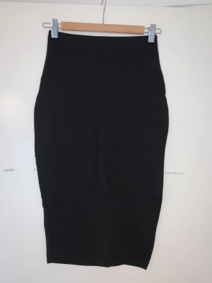 Pennkjol i trikå - Svart pennkjol i stretchig trikå i x small. Guldfärgat blixtlås bak. Mkt fint skick, endast använd 2 ggr.