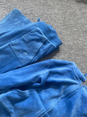 Juciy couture sett  - Säljer mitt ljus blå juciy sett pågrund av att den aldrig kommer till användning. Har använt det ett fåtal gånger, men är i ett väldigt bra skick. Storlek M men är exakt lika stort som S.