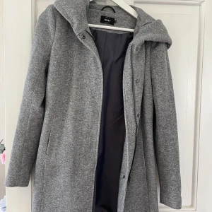 Vår/höst kappa från Only - Fräsch vår/höst kappa från Only i storlek XS. Nästintill oanvänd, använd få tal gånger men kappan ser ny ut. Stor luva och kappan går till mitten av låren.