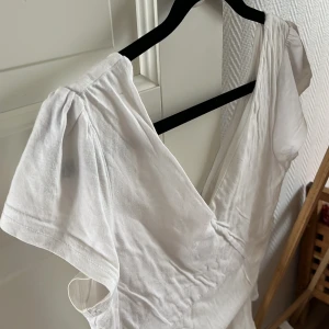 Vit topp blus bomull volangärm  - Vit topp med lite diskret volang på ärmarna och nedtill. Har en liten fläck på insidan av ena ärmen, ses sista bild, därav priset. Osäker på om den går bort med vaninish dock 🤔