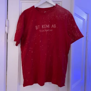 BT-Kemi AB - tshirt med självlysande tryck, XL - En styck tshirt med självlysande BT-Kemi AB-tryck på bröstet.  Med en design som ser ut att vara tämligen nedstänkt av Dinoseb eller något annat livsfarligt.