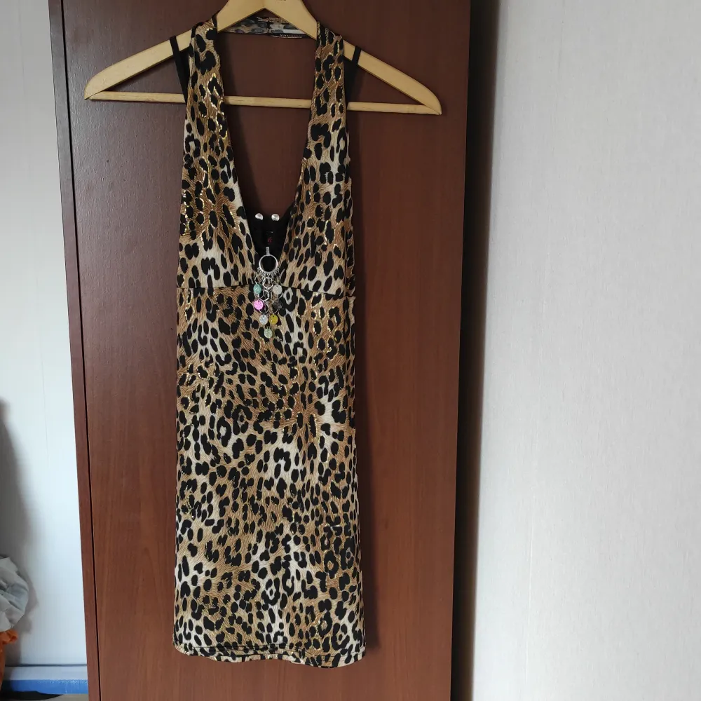 Snygg topp/kort klänning i leopardmönster och avtagbart paljettsmycke. Vintagefeeling. I nyskick och oanvänd. Färg: svart, brun, guld, beige.. Klänningar.