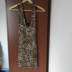 Topp/kort klänning leopardmönster - Snygg topp/kort klänning i leopardmönster och avtagbart paljettsmycke. Vintagefeeling. I nyskick och oanvänd. Färg: svart, brun, guld, beige.