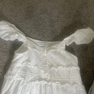 Vit långklänning med broderier  - Vit långklänning med blommor och broderier. I storlek 13-14 år men passar mig som är xs. Super fin till sensommaren. Passar att ha en tjocktröja över så klänningen blir en kjol.