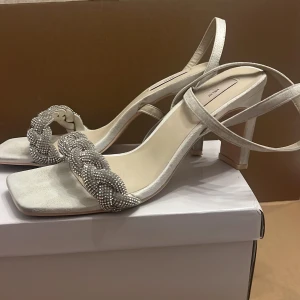 Klackarskor  - Inköpta på Nelly i juli månad. Använda 1 gång och är i väldigt bra skick. Storlek 38.  Vita med silvrig rem. 