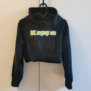 Svart croptop hoodie från Kappa! Märkt medium, men jag skulle säga att den är mer som en XS/S. Fräsig limegrön text! Köpt secondhand för flera år sen men kommer inte till användning längre.