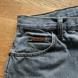 Wrangler jeans - Säljer dessa wrangler jeans i ljusgrått. Riktigt snygga med lite beiga detaljer. Sitter lite loose men inte för mycket. Passar dig som är runt 175 cm!