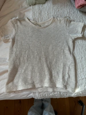 En vit glittrig tröja - En stickad t-shirt från Zara. Med silver glitter. Samt rosetter på axeln.