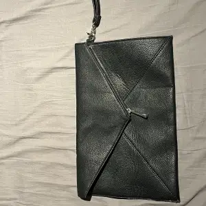 En svart handväska från Gina tricot gjord i fake skin med silveriga detaljer, stängs med silverig magnet knäppe, kanterna på den har små slitningar men inget man lägger stort märke till 