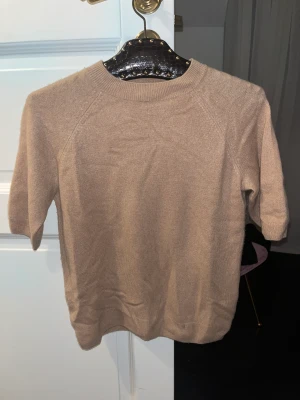 Cashmere T-shirt från H&M -  Beige jättefin Cashmere t shirt! Har ett litet hål (bild 3) vid tröjans mudd nedtill, knappt synligt💖