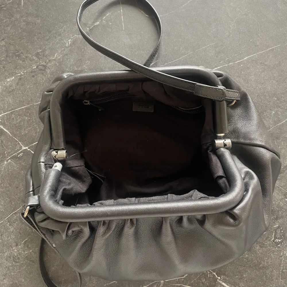 En svart axelremsväska från märket Wera, köpt på Åhléns för 1000 kr, och knappt använd efter det. Den är väldigt rymlig för att vara en liten väska.. Väskor.