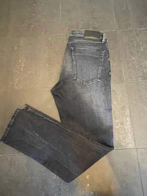 Säljer dessa stiliga Calvin Klein Jeans i modell Taper. De är svarta med toner av grått. De har använts vid få tillfällen och är därför i ”mint condition”. Storleken är 30/32. Hör av dig vid frågor eller funderingar.