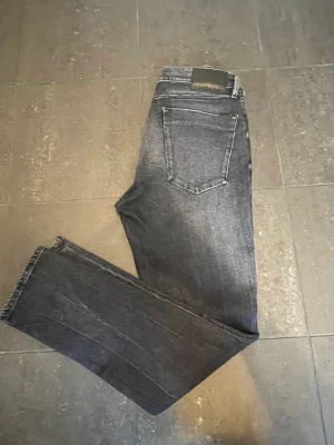 Calvin Klein Jeans Taper - Säljer dessa stiliga Calvin Klein Jeans i modell Taper. De är svarta med toner av grått. De har använts vid få tillfällen och är därför i ”mint condition”. Storleken är 30/32. Hör av dig vid frågor eller funderingar.