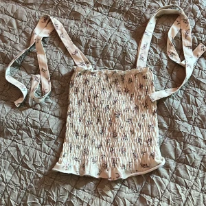 Gulligt linne från gina - Den är förliten för mig men är i bra skick! Den är 30cm uppifrån ner! Det finns snören på ärmbanden som kan knytas till rosetter. Skriv för mer!