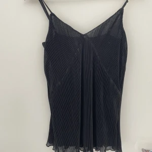 Linne - Ett svart trendigt luftigt linne med fina deltaljer nedtill. Fick det i present för några år sedan men har inte fått användning för det, det är oanvänt.