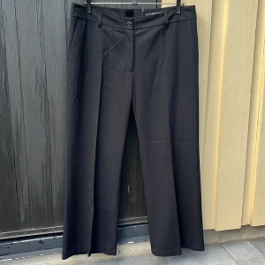 Svarta kostymbyxor  - Ett par svarta kostymbyxor i fint skick. Har två fungerande framfickor (bakfickorna är också riktiga men väldigt små) och justerbar midja, se bild 3. 64% polyester 34% viskos 2% elastin