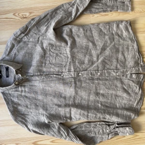 Linneskjorta J.Lindeberg - En linneskjorta från J.Lindeberg i beige. Knappt använd pga fel storlek.