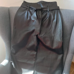 Svarta byxor  - Svarta utsvängda skinbyxor ifrån boohoo , aldrig använd lappen sitter kvar, fin till sommaren då modellen är kortare nertill 