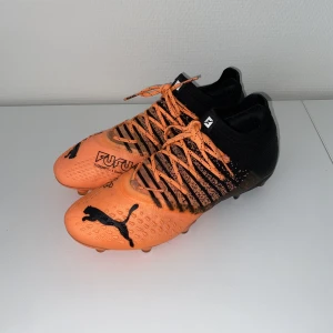 Fotbollsskor - Puma Future 1.3 Black/Orange - Använda en gång - nypris 2500 Storlek 41 / 26,5cm Sitter som storlek 42