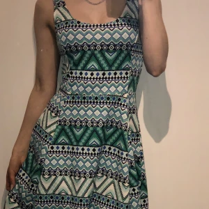 Klänning  - Klänningen har skönt material med olika färger och mönster. Klänningen har mest turkos i sig av färgerna. Vad färgen är vit.