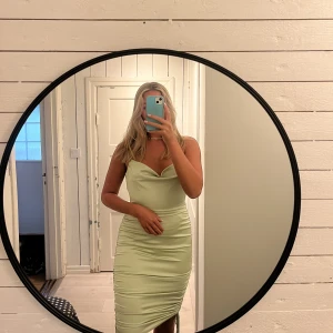 Grön klänning i satin  - Satinklänning från Nelly med öppen rygg och reglerbara band på sidorna som gör att man kan reglera klänningens längd! Storlek s