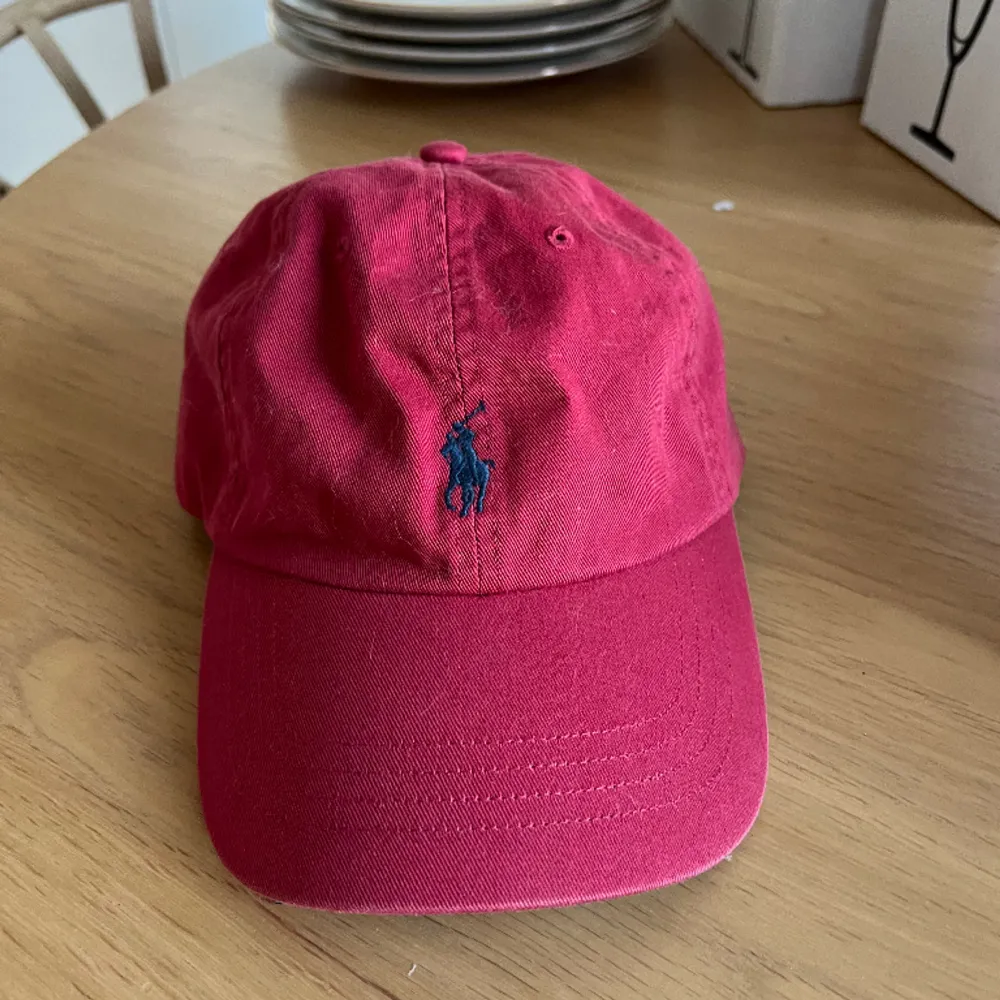 Röd keps från Ralph Lauren, den är solblekt samt lite smutsig på insidan som ni ser på bilden, har inte testat tagit bort men går säkert att tvätta bort. . Accessoarer.