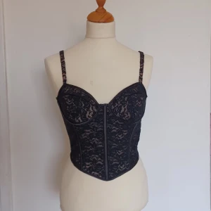 Korsett topp - Handsydd korsett-topp med kupor och boning, svart spets med nude mesh underlay. Perfekt skick. Passar XS med B/C-kupa