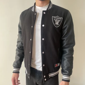 Svart collegejacka - Svart collegejacka med Amerikanska fotbollslaget Raiders logga på, jackan är av tjockare material och passar storlek M