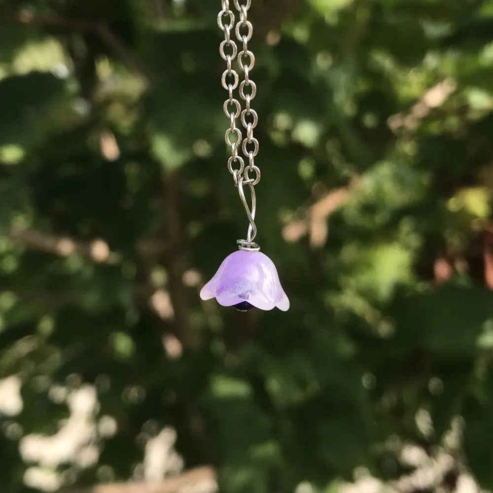 Lila halsbandshänge av glasblomma, silveromfattning och fossilsten. Nytt oanvänt och handgjort. Finns också i fler färger på min profil🌺kontakta gärna vid frågor☺️. Asusteet.