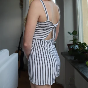 Byxdress vit med svarta ränder, knutning i ryggen - Vit byxdress med svarta ränder. Köpt i Spanien på strand marknad. Jätte skönt material och stretchig. Fin knutning i ryggen! Perfekt skick! Säljer för jag använder ej längre 🦓