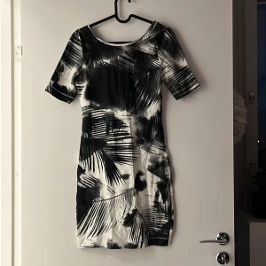 Klänning XS - Kortärmad klänning i figursytt material Grå/vit/svart mönstrad (palmer) Kappahl Storlek: XS/34  Aldrig använd, prislappar kvar!! 
