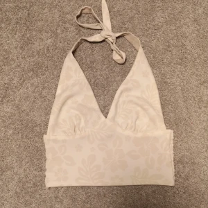 Två-sidig halternecktopp  - En supersnygg halterneck-topp från Bikbok som är helt ny och oanvänd. Den är tvåsidig (en beige och en vit sida med blommönster). I storlek XS. 